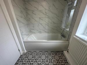 凯特林3 Bedroom House For Corporate Stays in Kettering的浴室铺有瓷砖地板,配有白色浴缸。