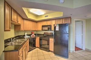 默特尔比奇Bayview Resort Penthouse w/ Sunset Views的厨房配有木制橱柜和黑色冰箱。
