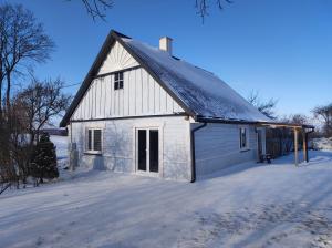 KrasnopolDom na Suwalszczyźnie的雪上带黑色屋顶的白色谷仓