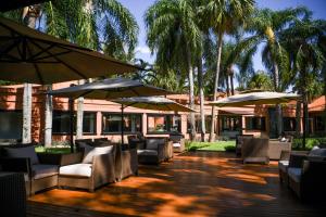 伊瓜苏Sanma Hotel的一个带椅子和遮阳伞及棕榈树的庭院