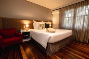 伊瓜苏Sanma Hotel的一间卧室配有一张大床和一张红色椅子