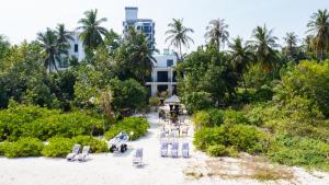 丹格迪Atoll Residence Dhangethi的享有海滩和大楼的空中景致,配有椅子