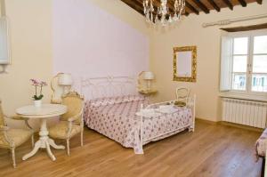 卢卡安菲堤亚特洛B&B酒店的卧室配有粉红色的床和桌椅