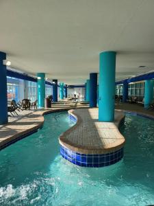 默特尔比奇Bayview Resort Penthouse w/ Sunset Views的一座建筑物内一座拥有蓝色柱子的游泳池