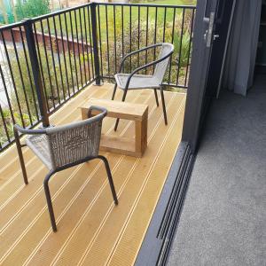 巴尔克拉萨Piwakawaka Suite的阳台上配有两把椅子和一张木桌