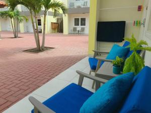 棕榈滩Aruba Condo The Pearl - At Eagle Beach - minute walk!的一座带蓝色椅子和棕榈树的庭院