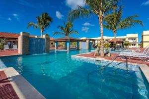 棕榈滩Aruba Condo The Pearl - At Eagle Beach - minute walk!的一座拥有蓝色海水和棕榈树的游泳池