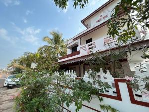 拉特纳吉里Gayatri Homestay的前面有树木的白色建筑