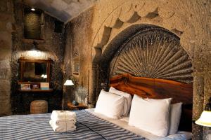 格雷梅Goreme Suites by AZA的卧室配有一张石墙内的大床