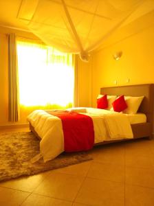 KakamegaMusundi Luxury Homes的一间卧室配有一张带红色和白色枕头的大床