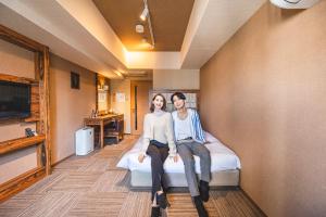 大阪难波大国町瑞利弗酒店的坐在床上的男人和女人
