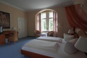 Derenburg德朗堡城堡别墅酒店的一间卧室设有两张床、一张桌子和一个窗口。