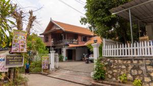 琅勃拉邦Mao Pha Sok Guesthouse的一座房子,上面有白色的栅栏和标志