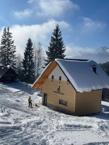 耶塞尼采Alpine Cottage Golica的站在雪中小屋前面的人