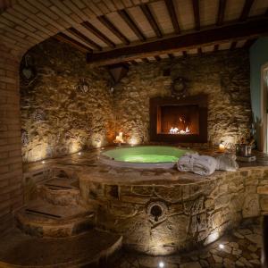 圣奎里科-多尔恰PALAZZO DEL CAPITANO Wellness & Relais - Luxury Borgo Capitano Collection的石质浴室设有壁炉、浴缸和
