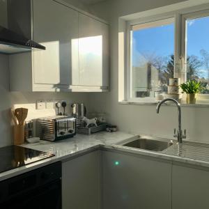 Lovely two bedroom Annexe close to Newbury的厨房配有白色橱柜、水槽和窗户。