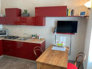 帕维亚PAVIA CENTRO的一间设有红色橱柜和木桌的小厨房