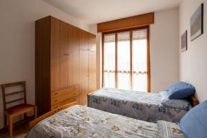 比耶拉Appartamento vista Alpi biellesi的一间卧室设有两张床、一把椅子和一个窗户。