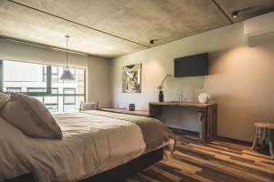 埃斯特角城Be House Suites & Spa的卧室配有一张床,墙上配有电视。