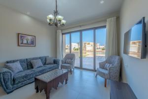 赫尔格达Brand-New Family House in Tawila El Gouna Lagoon and Pool Access的客厅配有沙发、两把椅子和电视