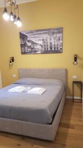 米兰MagnoliaApartments - 18B Visconti Duomo的卧室内的一张床铺,墙上有绘画作品