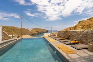 Merchia BeachThe Mykonist Merchia Beach Villas & Suites的一个带椅子的游泳池,享有海景