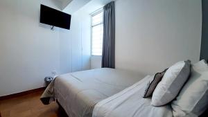 塔克纳Majhu Hostal的一间卧室配有一张带白色床单的床和一扇窗户。