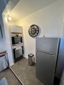 GagnySuper appartement chaleureux à 30min de Paris的厨房配有冰箱和墙上的时钟
