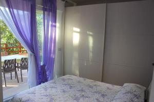 奥梅尼亚Casa Simone的一间卧室配有一张床和一个带紫色窗帘的窗户