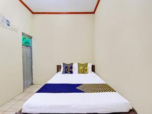 GlagahSPOT ON 92220 Sari Laut的一间卧室配有一张带蓝色和黄色枕头的大床