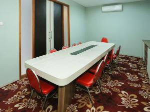 雅加达Super OYO Townhouse OAK Hotel Fiducia Pondok Gede的一间会议室,配有白色的桌子和红色的椅子