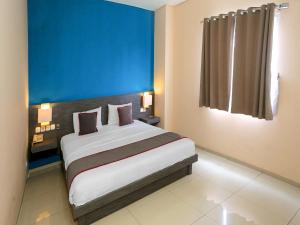 雅加达Super OYO Townhouse OAK Hotel Fiducia Pondok Gede的一间卧室设有一张蓝色墙壁的大床