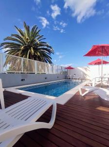 科隆Catalina Hotel的一座带白色椅子和棕榈树的游泳池