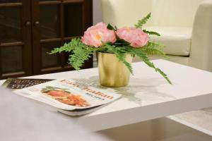 多伦多Home Away From Home - Basement Studio Apartment的一张带杂志的桌子上装有粉红色花的花瓶