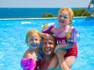 古兹耶姆5 person holiday home on a holiday park in Gudhjem的游泳池里的一个男人和两个女孩