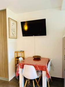帕皮提Tehautahi Cozy Lodge的餐桌、椅子和墙上的电视