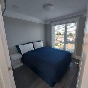 温哥华Beautiful Bright 3 Bed Townhouse的一间卧室设有蓝色的床和窗户。