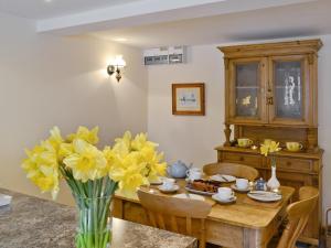 纽兰Honey Cottage的一间用餐室,配有一张带黄花花的花瓶