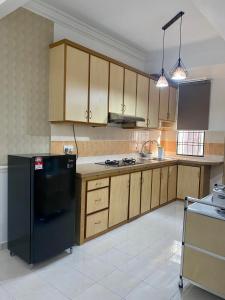 Kampong Belah DuaComfy Sutera Seberang Jaya的厨房配有黑色冰箱和木制橱柜。