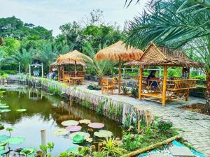 北榄Ban Ing Suan的一间带桌椅的餐厅和一个养有百合花的池塘