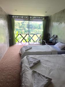 琅勃拉邦Mao Pha Sok Guesthouse的客房设有三张床和大窗户