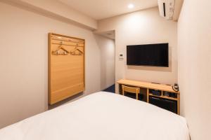 大阪Sotetsu Fresa Inn Yodoyabashi的一间卧室配有一张床、一张书桌和一台电视