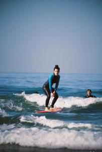 塔姆拉赫特乌兹达尔Arima Surf House的一名年轻人在海浪冲浪板上挥手