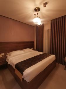 Umm UthainahDara apartment hotel的一间卧室配有一张大床和一个吊灯。