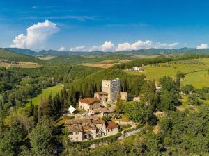 基安蒂盖奥勒Castello Di Tornano Wine Relais的田野上山丘上的一座老房子