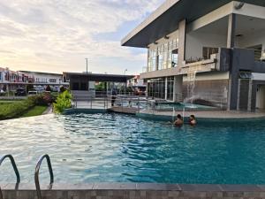 帕帕尔RHR Deluxe GuestHouse Kinarut Papar Sabah - Pool View的两人在大楼前的游泳池里