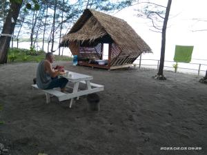 古达Tammoyo Place的坐在小屋旁野餐桌上的人