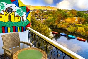 阿斯旺Onaty Ka Guest House的阳台配有椅子和遮阳伞,享有河流美景。