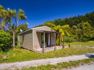 塔卡卡Bay Cottage - Takaka Holiday Unit的棕榈树海滩上的小屋