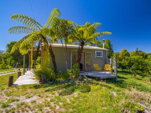 塔卡卡Bay Cottage - Takaka Holiday Unit的小房子,带两把椅子和棕榈树